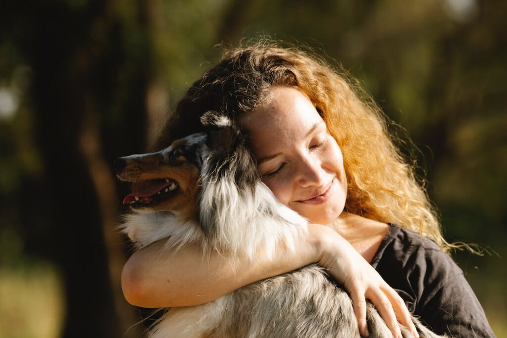 A woman hugging a dog to create a Positive Environment for good Animal Behavior.